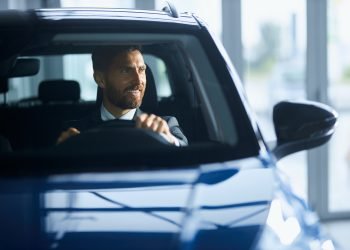 Businessman in suit buying new car at modern salon