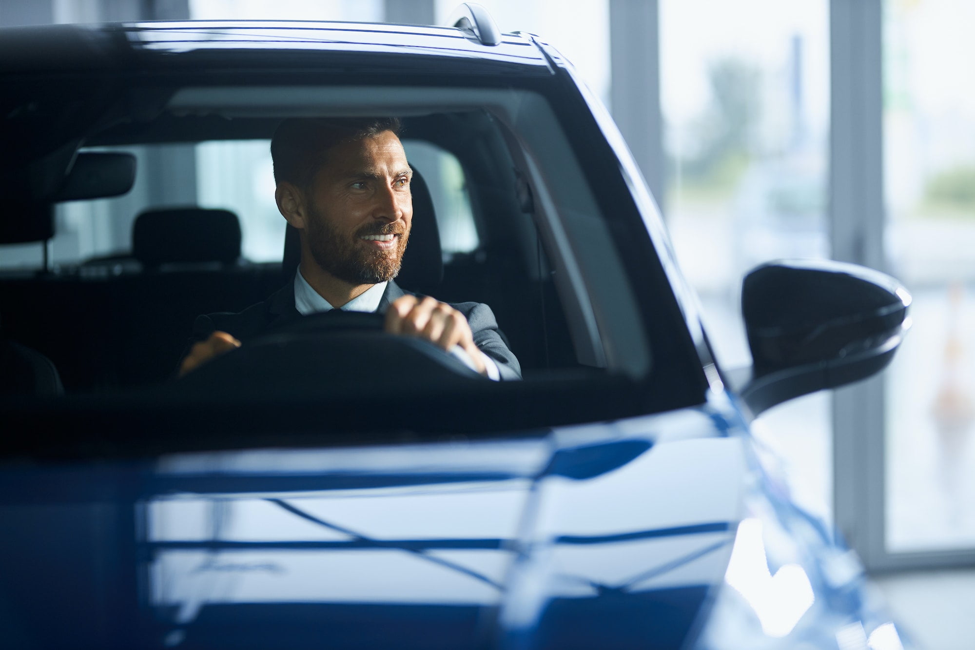 Businessman in suit buying new car at modern salon